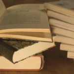 Bücherstapel in warmem Licht, darauf ein aufgeschlagenes Buch.